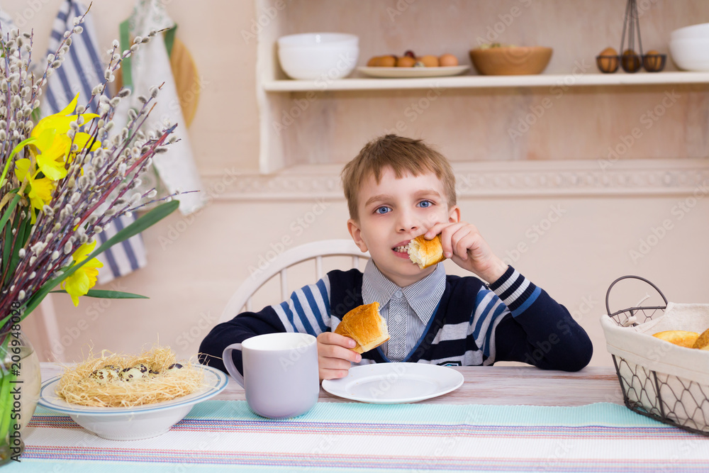 The boy is eating a croissant in the breakfast The boy is eating a croissant in the breakfast