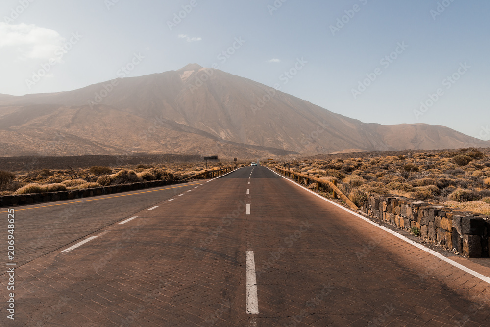 Road to El Teide volcano peak. Travel by car. Volcanic fields on the volcano. Landscape with road in Teide National Park, Tenerife, Canary Island, Spain