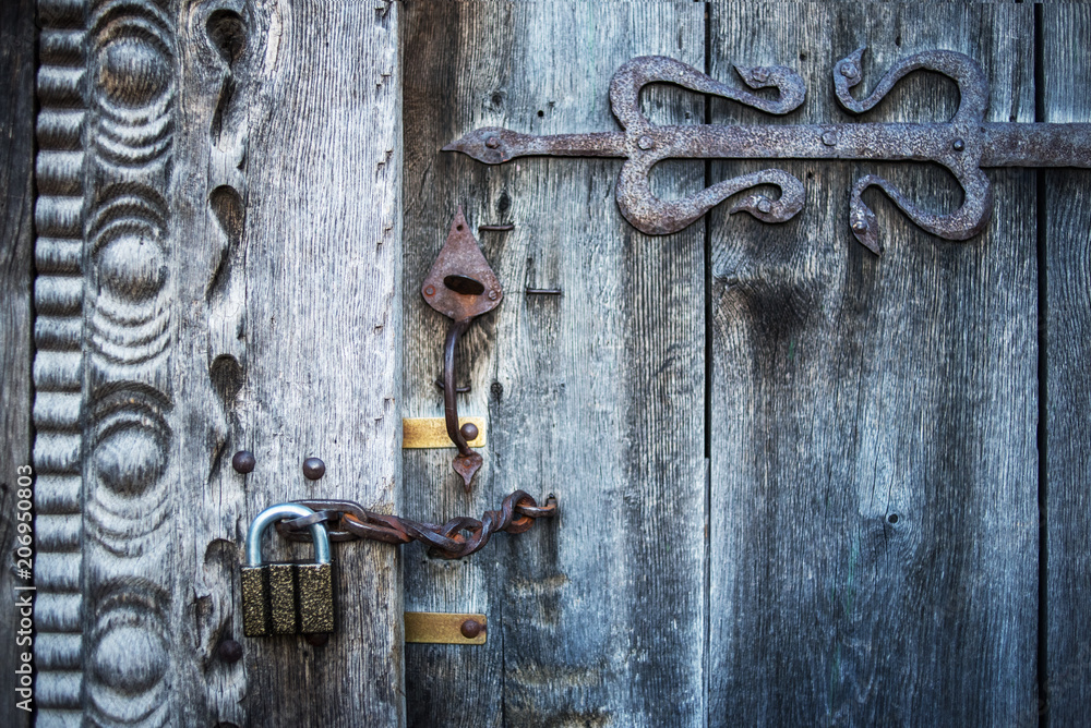 Old wooden gate closed on rusty padlock, texture