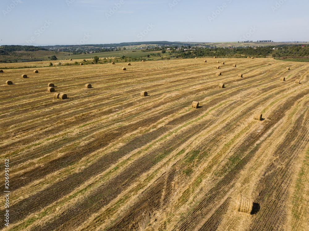 Aerial view to harvested field with straw bales in summer