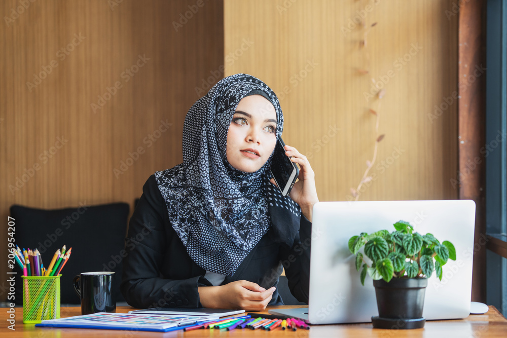Muslim businesswoman using smartphone and laptop at office Muslim businesswoman using smartphone and laptop at office