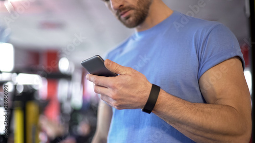Athlete launching application on smartphone to synchronize with fitness bracelet