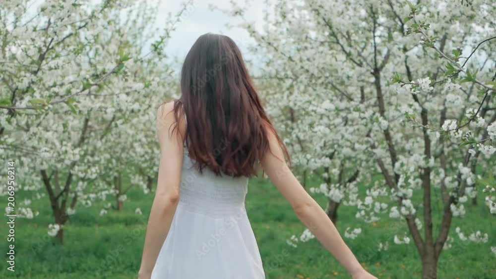 spring fashion portrait of a beautiful happy young woman in white dress with long brown hair run and enjoy smell flowers in the blossoming garden spring fashion portrait of a beautiful happy young woman in white dress with long brown hair run and enjoy smell flowers in the blossoming garden