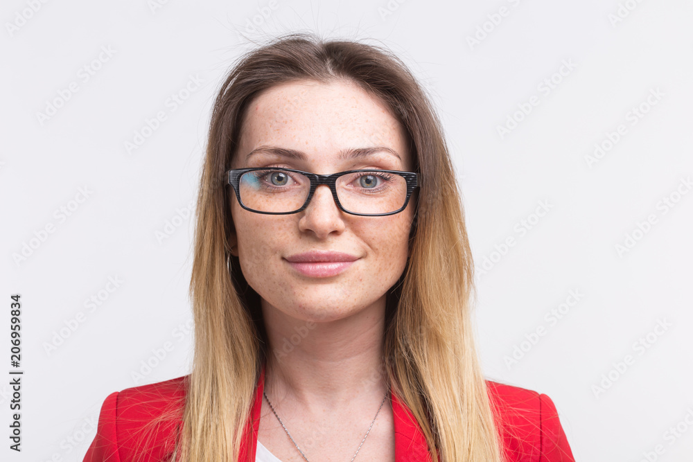Portrait of young freckled woman wearing glasses against white background