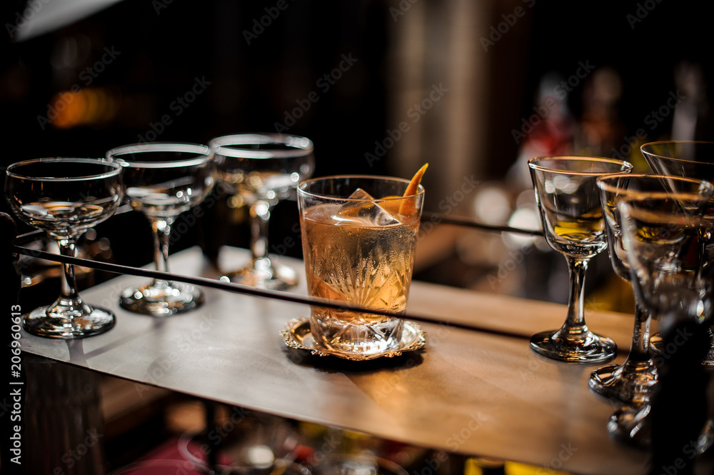 Delicious old fashion cocktail in the glass standing among empty glasses Delicious old fashion cocktail in the glass standing among empty glasses