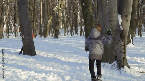 Three brothers play snowballs at winter park, slow motion photo