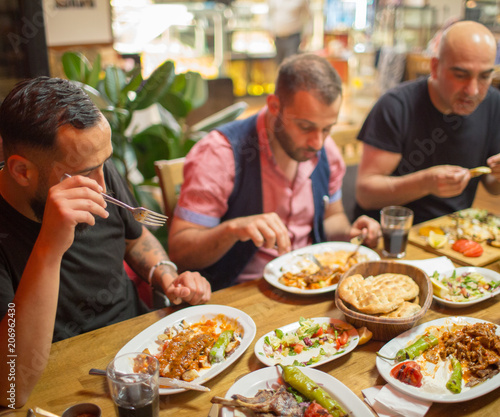 Group of Muslim people in restaurant enjoying Middle Eastern food. Selective focus