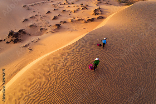 Woman carrying flower basket at sunset in Mui Ne sand dune, Vietnam