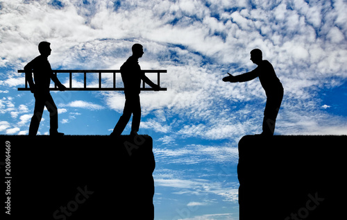 Silhouette two men carry a ladder to pave the way across the abyss for another man