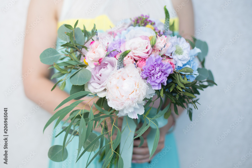 Close up of bouquet in hands of a girl in mint and yellow dress. Gentle bridal mixed flowers bouquet with blue hydrangea, violet carnation, blue scabiosa, purple roses, white peony, violet waxflower Close up of bouquet in hands of a girl in mint and yellow dress. Gentle bridal mixed flowers bouquet with blue hydrangea, violet carnation, blue scabiosa, purple roses, white peony, violet waxflower