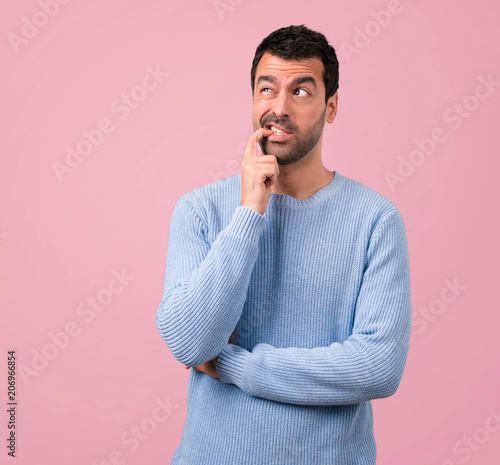 Handsome man having doubts and with confuse face expression on pink background