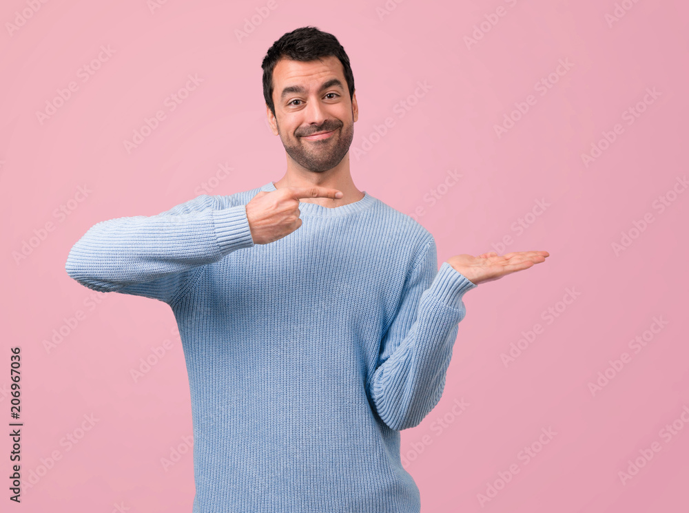 Handsome man holding copyspace imaginary on the palm on pink background Handsome man holding copyspace imaginary on the palm on pink background