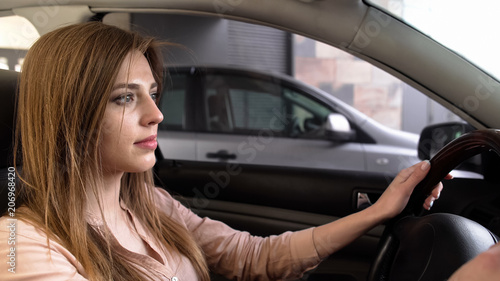 Young woman driving out from parking place, steering confident, attentive