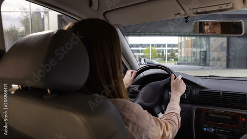 Business person sitting in car, female driver, comfortable transport, back view © motortion