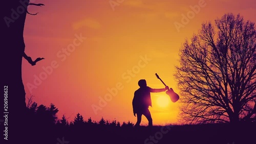 Male musician with guitar in hand at sunset in the Park