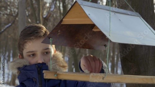 Teenager put small piece of bread in bird feeders photo