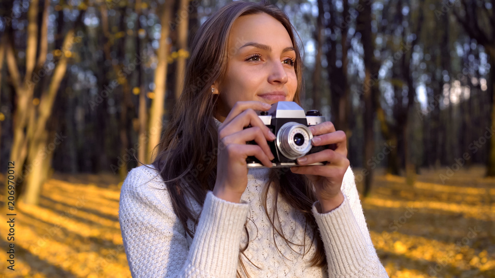 Lady admiring autumn, trying to capture moment with old vintage camera, hobby