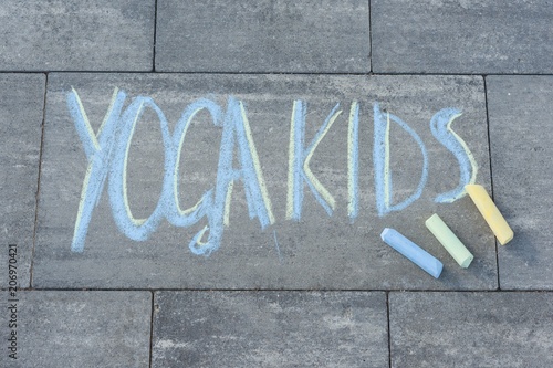 Yoga kids text written by children on the paving slab with colored crayons