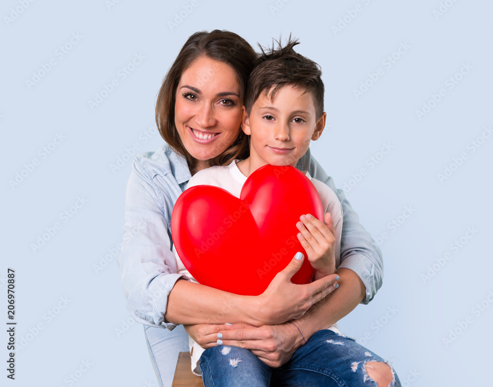 Mother and daughter holding a big heart icon toy on blue background Mother and daughter holding a big heart icon toy on blue background