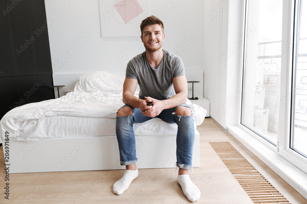 Smiling young man sitting with tv remote Smiling young man sitting with tv remote