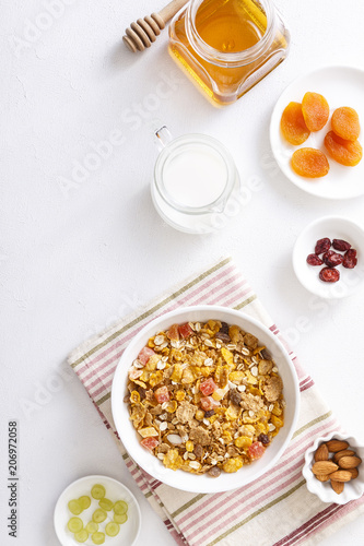 Muesli served with milk  honey  almonds  dried apricots and dried cranberries. Vertical shot. Flatlay.
