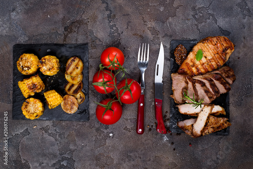 Fresh three types of grilled steak on slate plate with herbs, corn, tomato and grilled potatoes