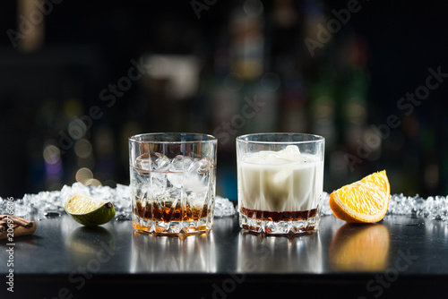 Two glasses of alcoholic drinks with ice on the table. With slices of lime and orange.