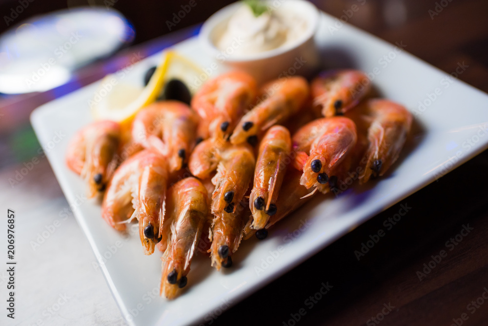 Appetizer of a boiled shrimp on a white plate with a white sauce