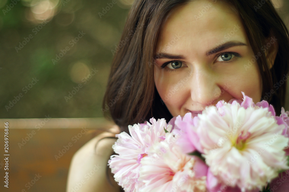 Pretty young beautiful woman on a bench with peony flowers and shining sun. Place for text Pretty young beautiful woman on a bench with peony flowers and shining sun. Place for text