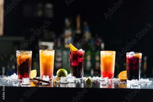 Canvas Print Multi-colored alcoholic cocktails with citrus in glasses of different shapes on the bar