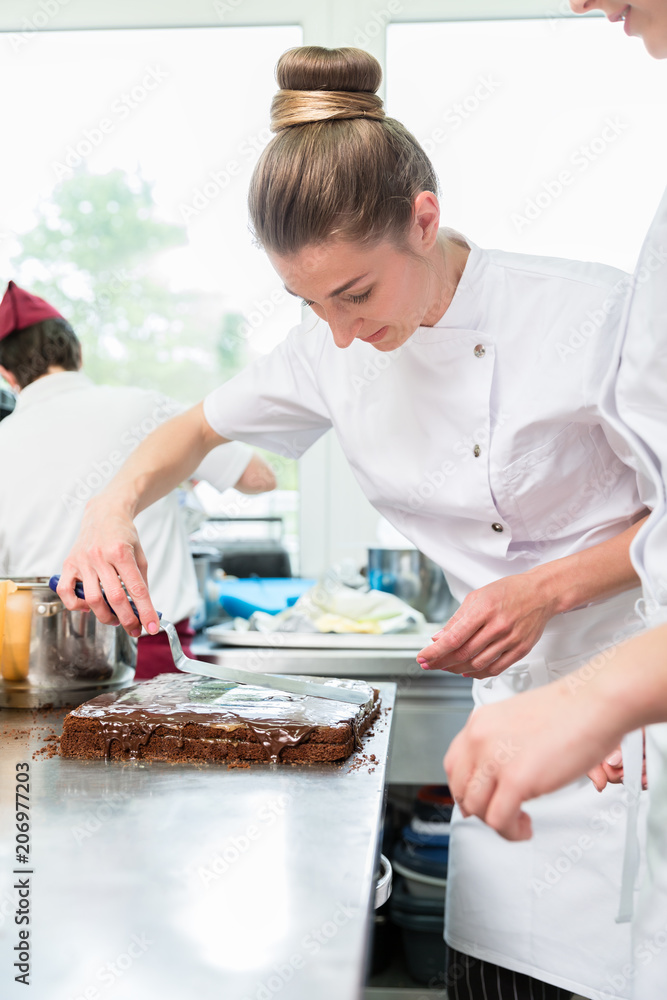 Confectioner putting chocolate as frosting on cake Confectioner putting chocolate as frosting on cake