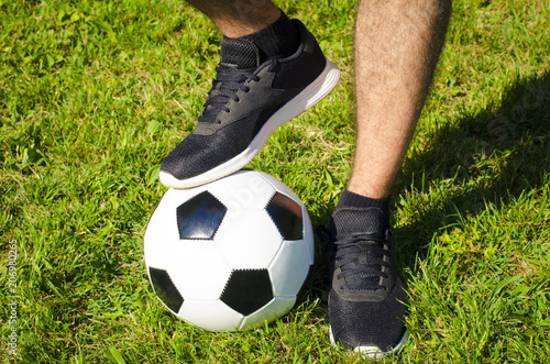 The man's leg in sneakers and soccer ball