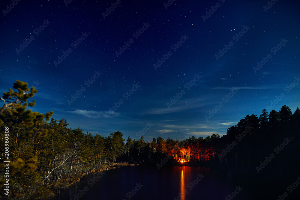 Lake with campfire at night starry sky