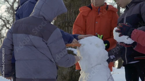 Five boys make snowman together in winter park photo