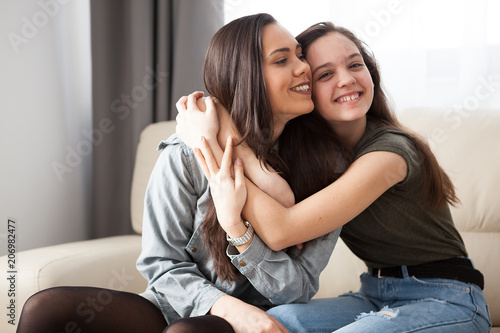 Two sisters next to each other in the living room simling and having fun