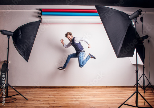 Portrait of a young hipster man in a studio, jumping. Copy space. photo