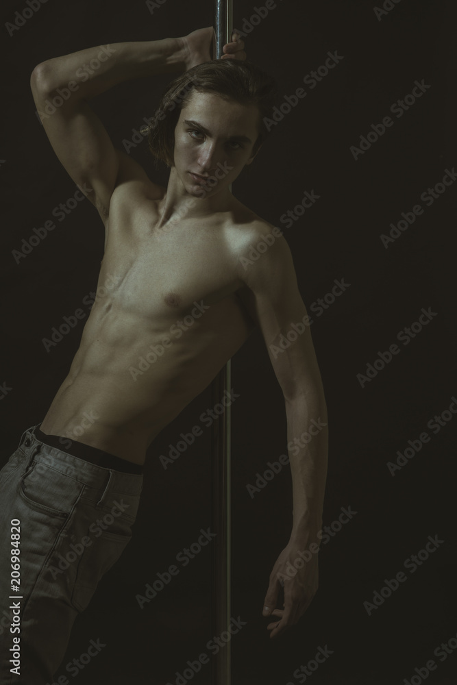 Naklejka premium Sexy, attractive guy lean on metallic pole.