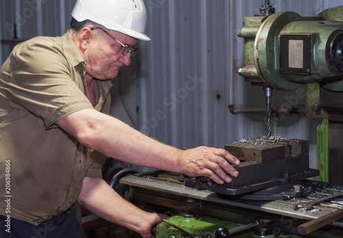 Old machinist working a metal lathe