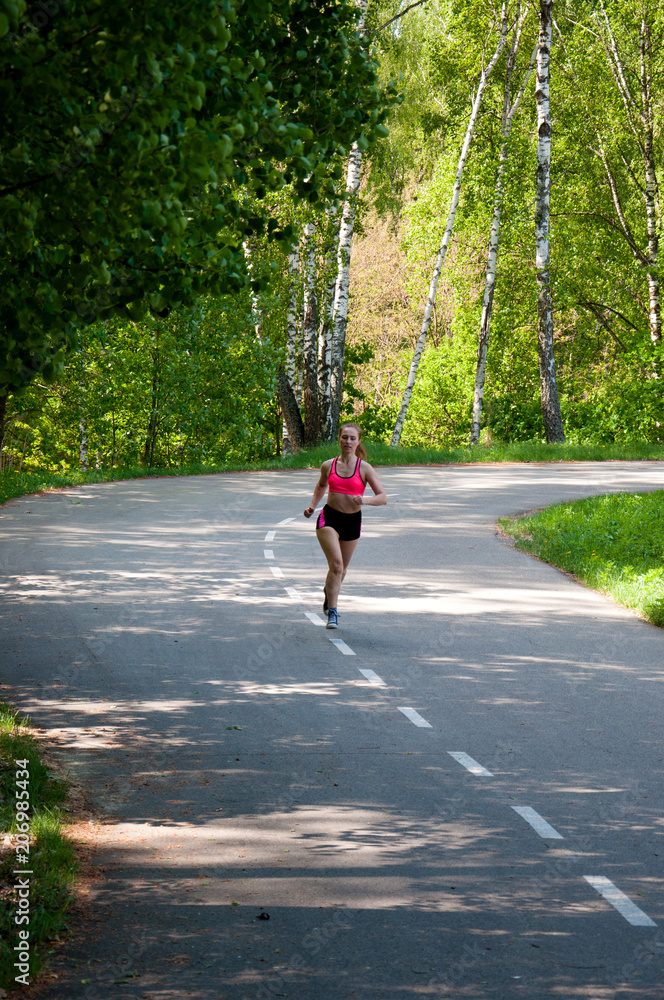 Beautiful smiling woman running in the park in the morning. Fitness girl running in the park. Running woman. Female Runner Jogging during Outdoor Workout in a Park. Beautiful fit Girl. Beautiful smiling woman running in the park in the morning. Fitness girl running in the park. Running woman. Female Runner Jogging during Outdoor Workout in a Park. Beautiful fit Girl.