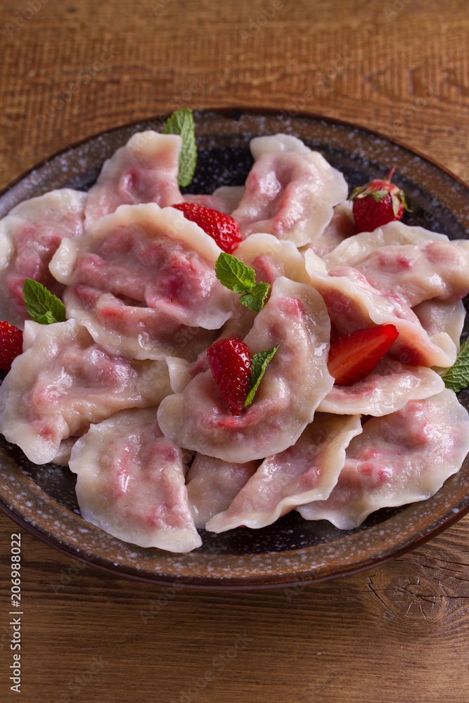 Dumplings, filled with strawberries. Pierogi, varenyky, vareniki, pyrohy - dumplings with filling. View from above, top, overhead