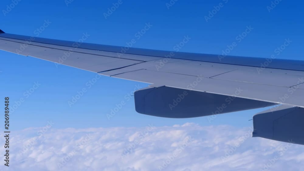 An airplane is flying above the clouds. A wing is seen from the window of the plane. An airplane is flying above the clouds. A wing is seen from the window of the plane.