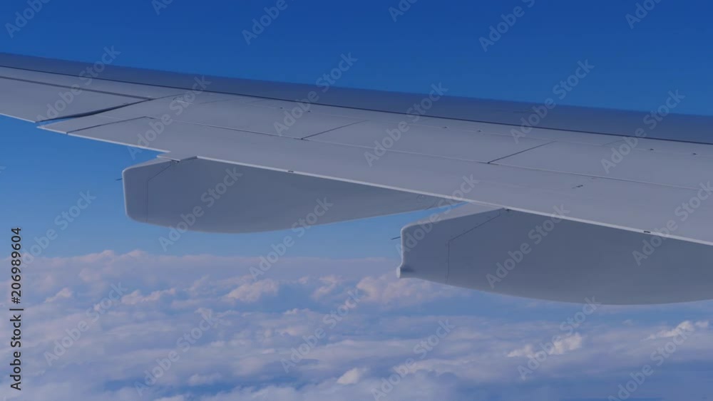 An airplane is flying above the clouds. A wing is seen from the window of the plane. An airplane is flying above the clouds. A wing is seen from the window of the plane.