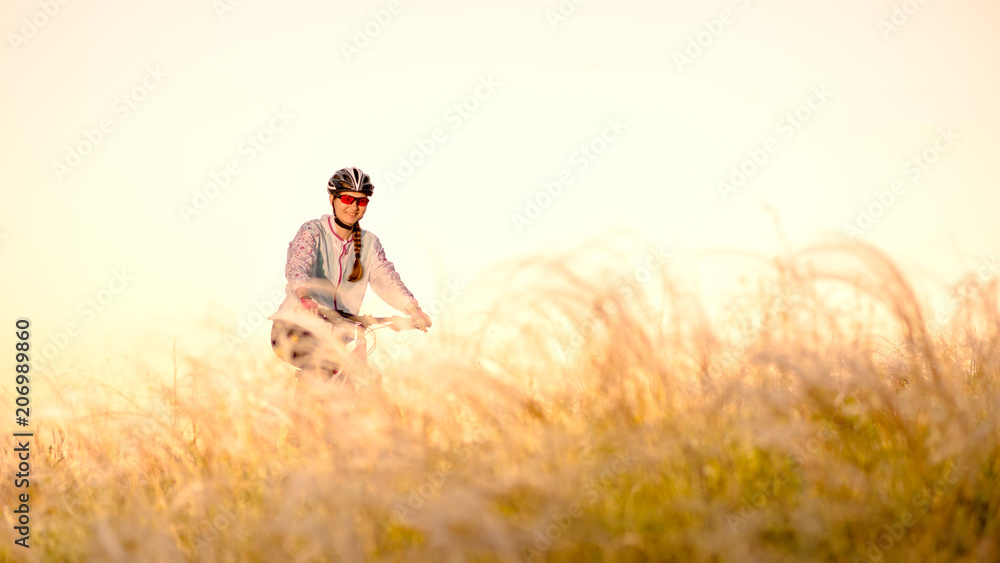 Young Woman Riding Mountain Bikes in the Beautiful Field of Feather Grass at Sunset. Adventure and Travel. Young Woman Riding Mountain Bikes in the Beautiful Field of Feather Grass at Sunset. Adventure and Travel.