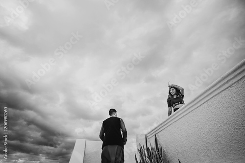 Drama black and white picture of Hindu groom walking up to bride while she stands on the balcony photo