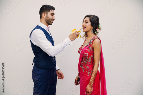 Hindu groom feeds bride in pink sari with a banana photo