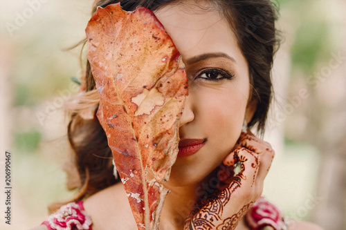 Hindu bride holds autumn leaf before her face photo