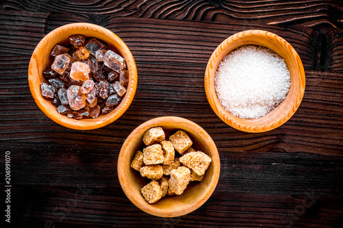 lumps of sugar in bowls on wooden table background top view