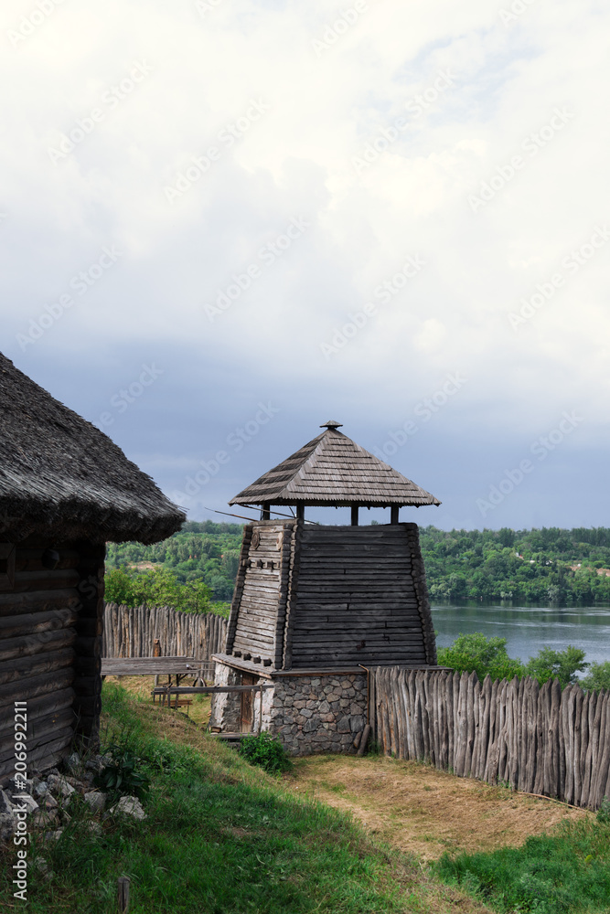 ancient fortification of a wooden palisade, of Cossack state guard army troop. Panoramic view from Khortytsia island on broad Dnipro summertime, wooden church and houses construction technology ancient fortification of a wooden palisade, of Cossack state guard army troop. Panoramic view from Khortytsia island on broad Dnipro summertime, wooden church and houses construction technology