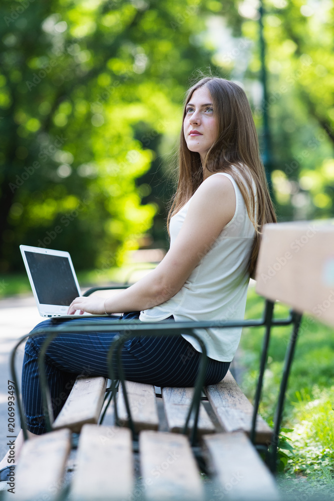 Young dark blonde girl studying in a park with a laptop Young dark blonde girl studying in a park with a laptop