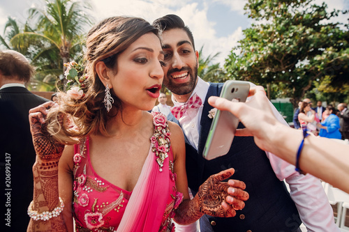 Indian bride and groom look at the picture in a smartphone